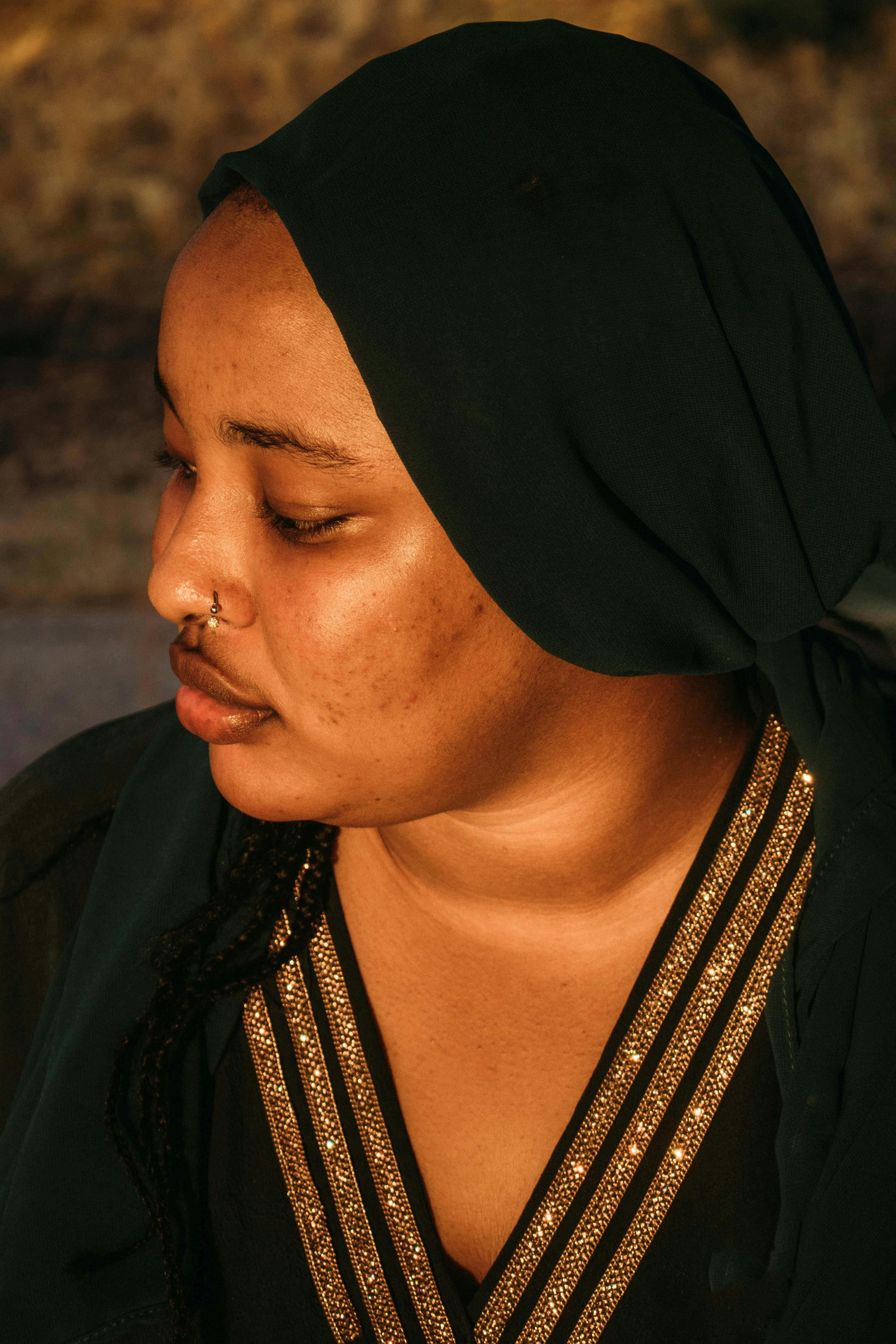 Profile of a woman in a traditional headscarf with reflective expression.