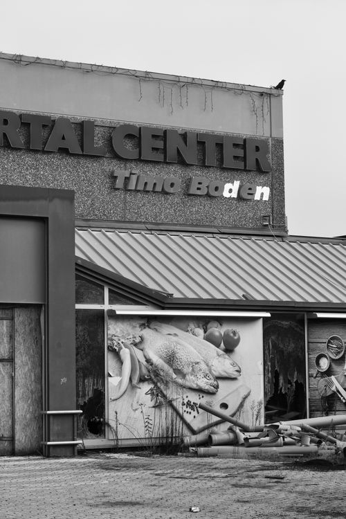 Free Black and white image of an abandoned shopping center with deteriorating signage and artwork. Stock Photo