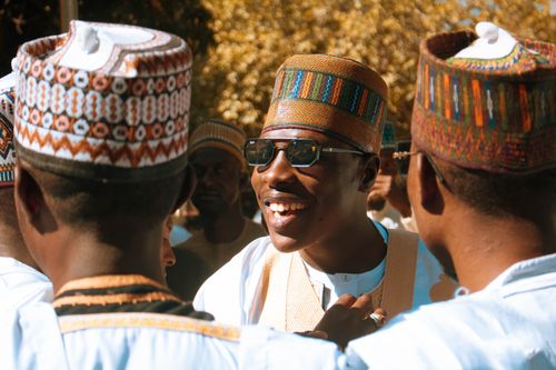 Free Group of men in traditional attire enjoying a sunny outdoor celebration. Stock Photo