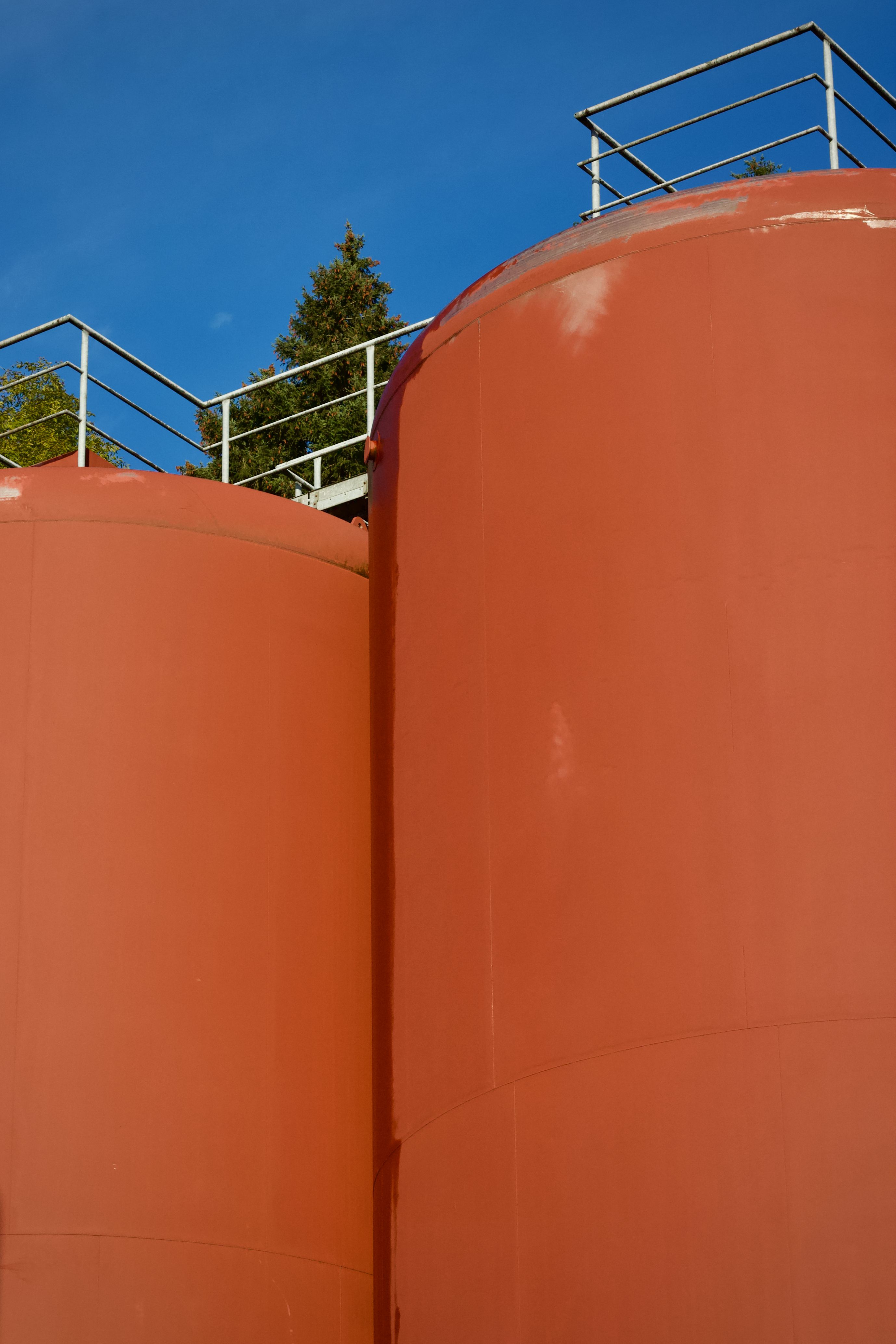Bright Orange Industrial Storage Silos Against Blue Sky · Free Stock Photo