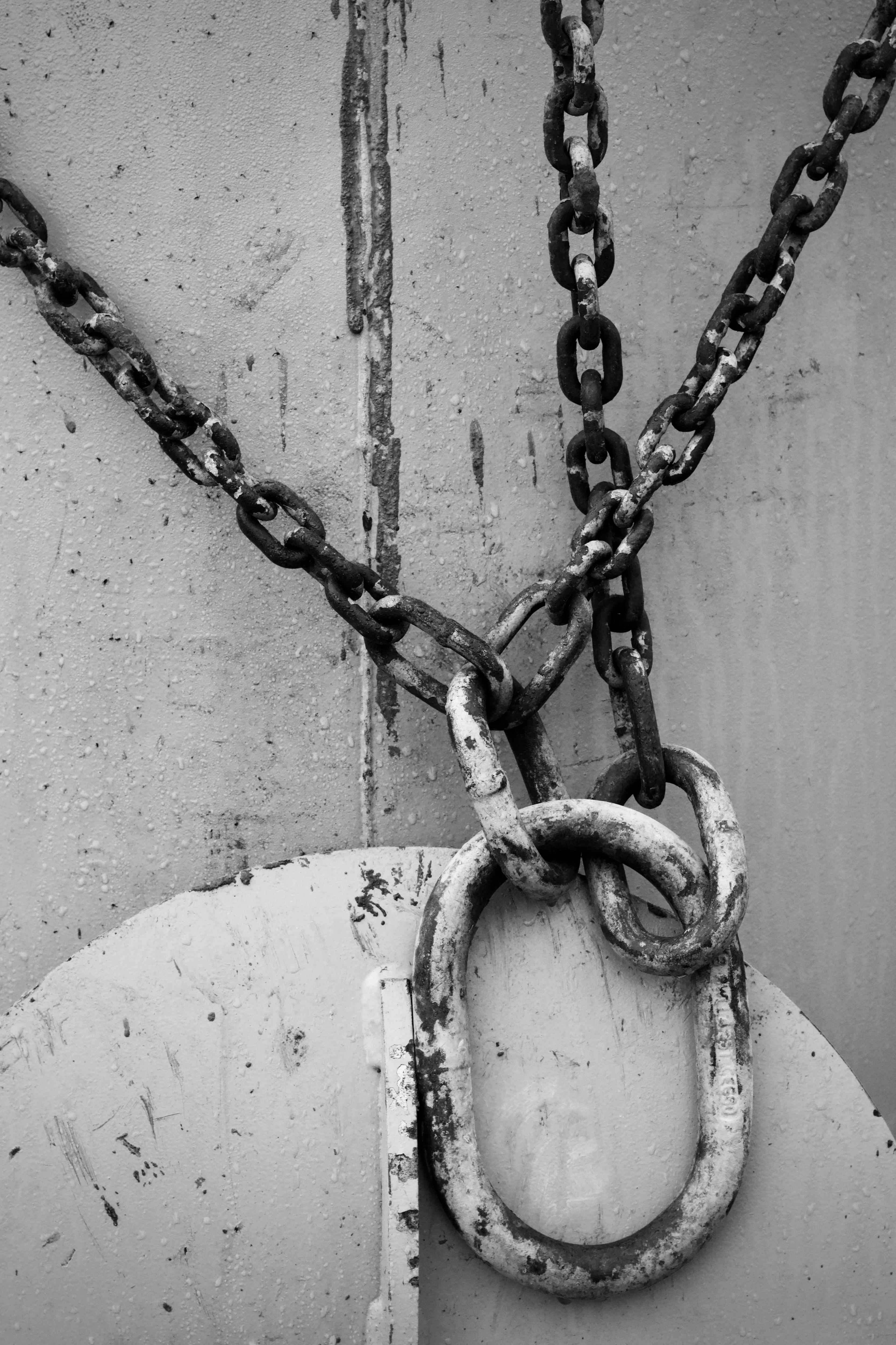 Monochrome image showcasing worn metal chains against a textured background, evoking industrial strength and durability.