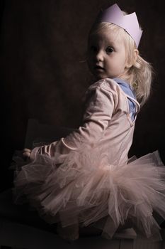 Charming portrait of a young child wearing a tutu and paper crown, exuding a whimsical fairy tale vibe.