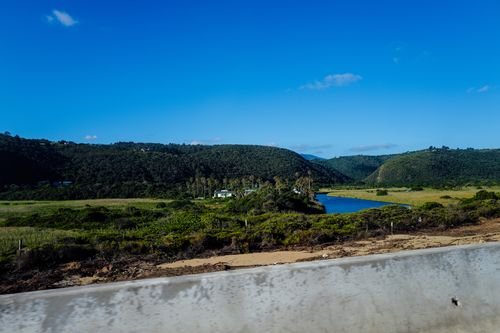 Free A beautiful landscape of a lush valley with a river under a clear blue sky. Stock Photo