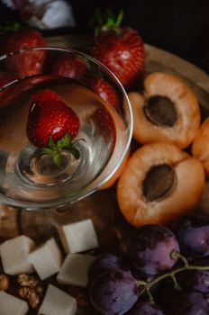 A vibrant display of strawberries, grapes, apricots, cheese, and a glass of wine, perfect for elegant dining.