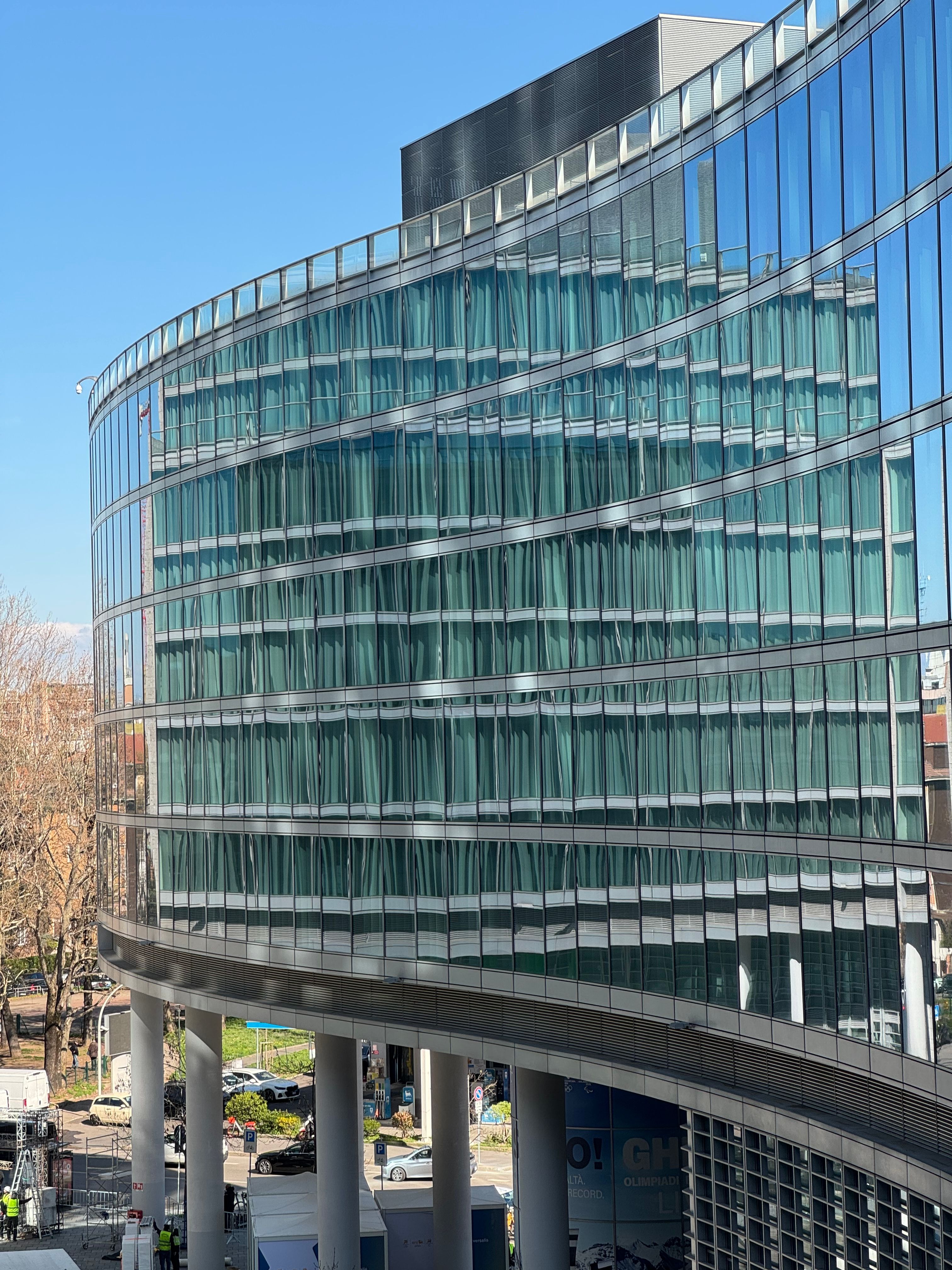 Fotomural Fachada de cristal curvado de un moderno edificio de oficinas en Milán, Italia, en un día soleado.