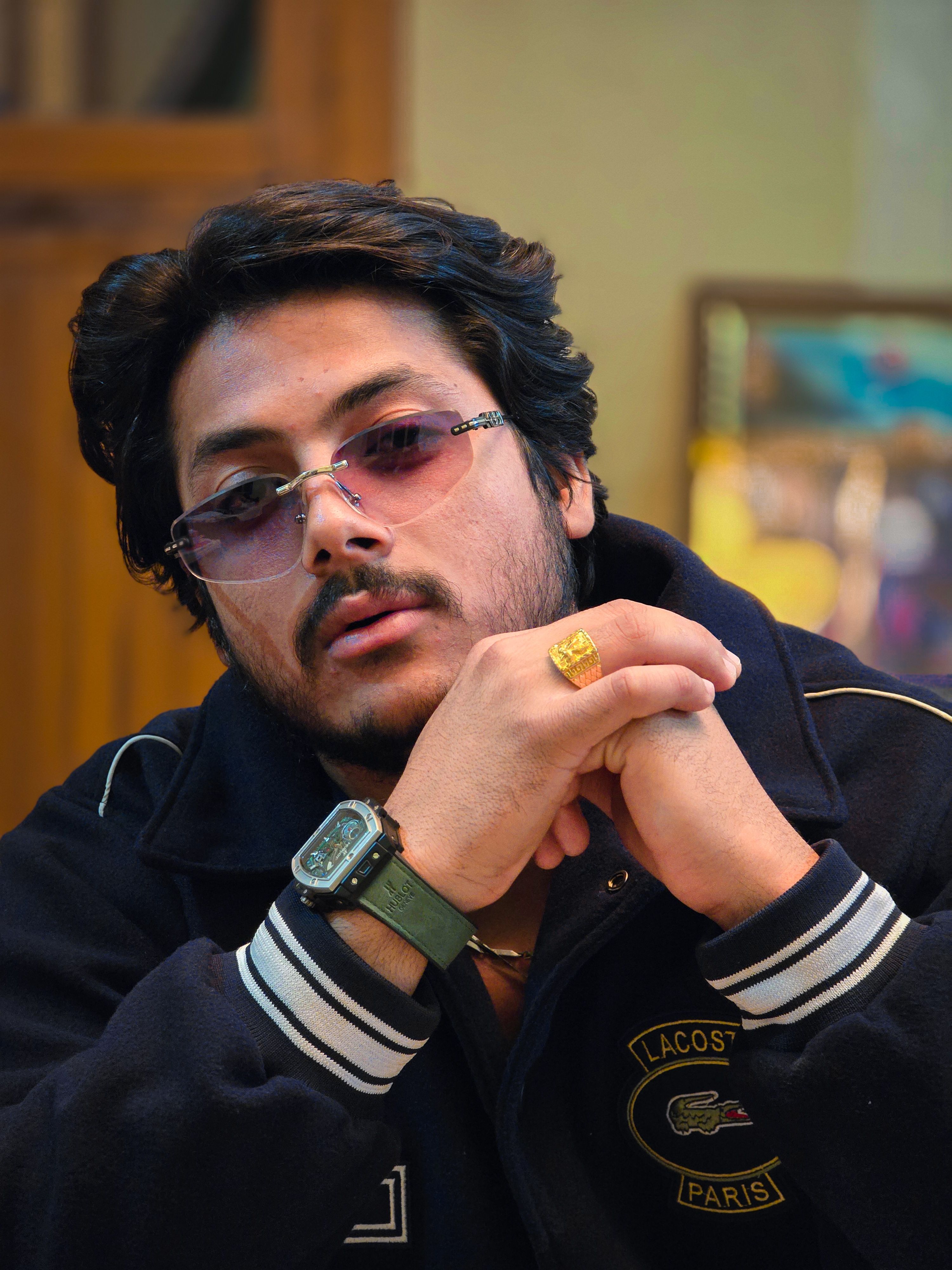 Portrait of a stylish man with glasses indoors, showcasing casual fashion and elegance.