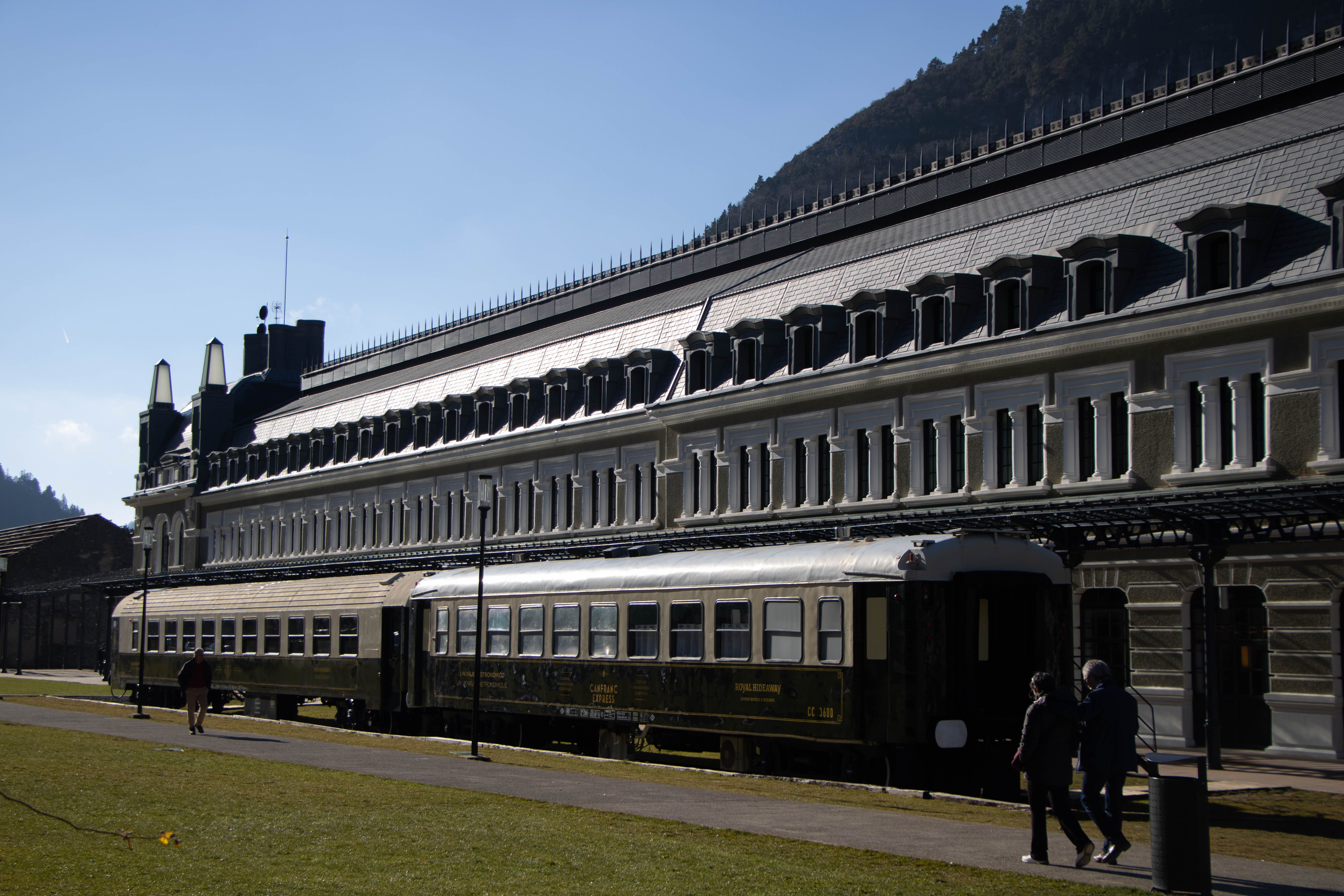 Classic station scene with luxury train awaiting boarding under mountain light