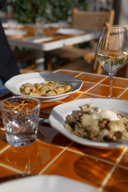 Free Delicious pasta dishes and wine on a sunlit outdoor table in Sydney, Australia. Stock Photo