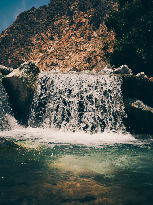 Free Experience the tranquil beauty of a waterfall nestled in the rocky landscape of Khourfakkan, UAE. Stock Photo