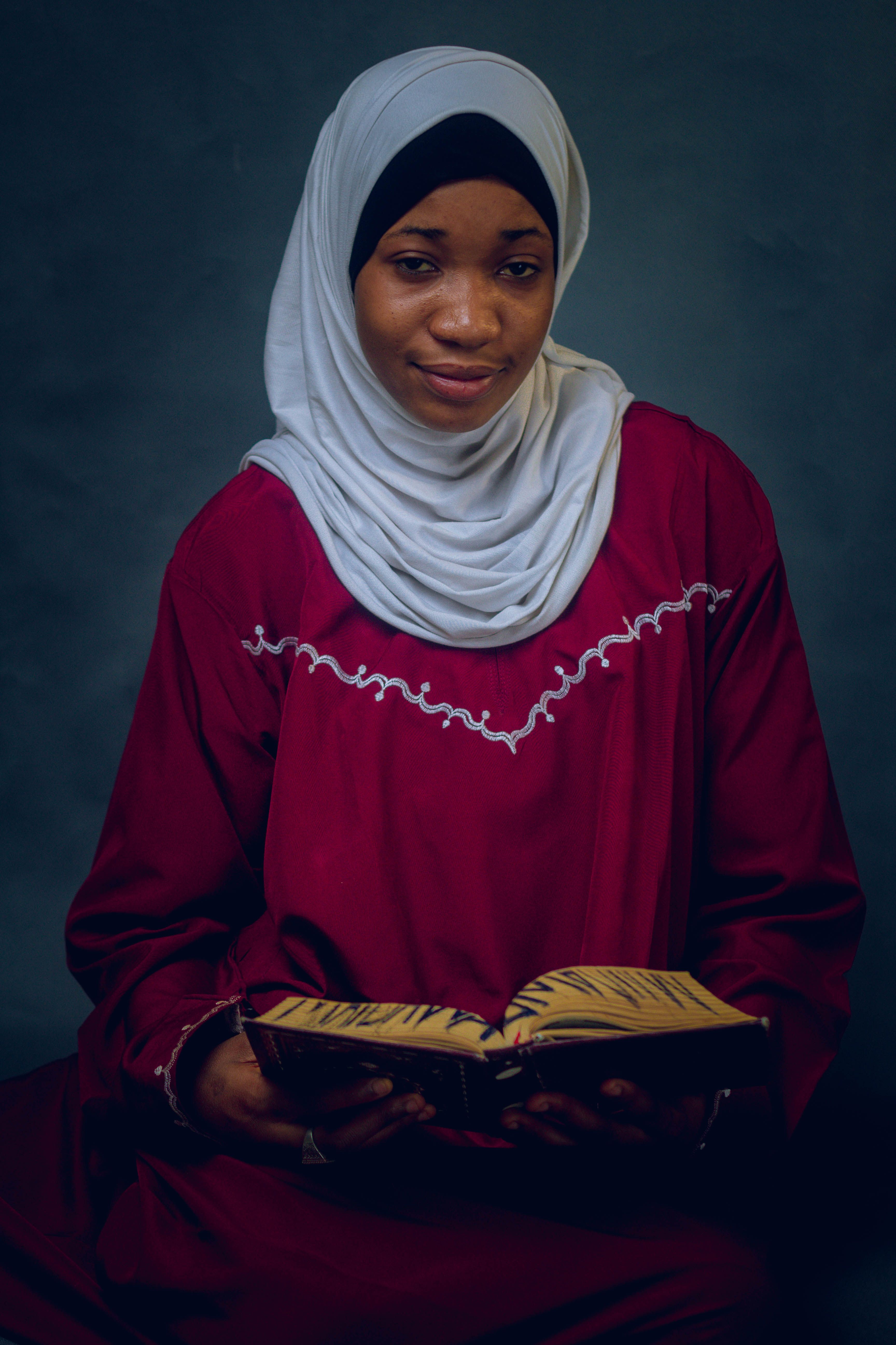 Young Woman in Hijab Reading a Book Indoors · Free Stock Photo