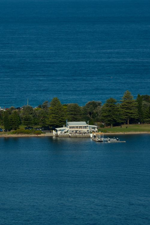 Free A scenic view of a waterfront pavilion surrounded by lush greenery and ocean in Sydney, Australia. Stock Photo