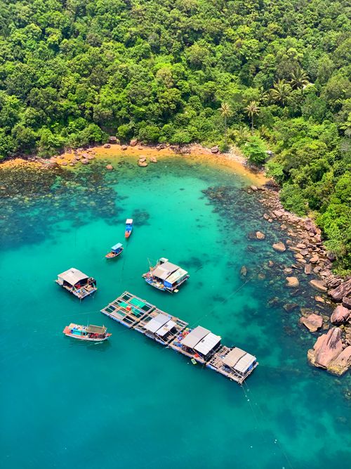 Free Aerial shot of floating houses on emerald waters against lush greenery. Ideal for travel and nature themes. Stock Photo