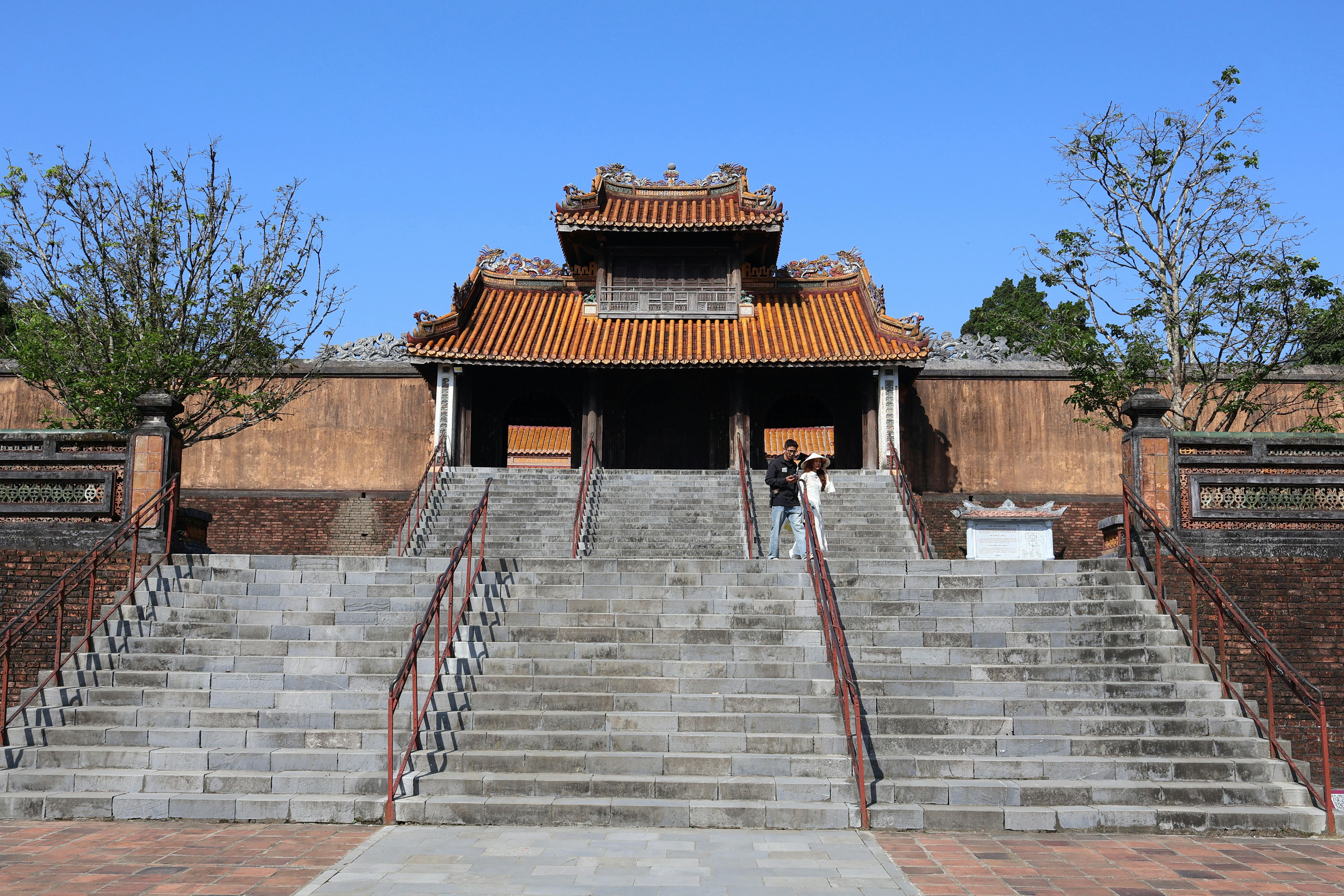 A couple explores the entrance of the historic Hue Imperial City on a sunny day.