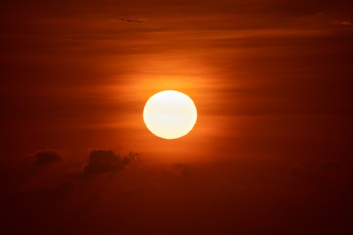 Free Captivating sunset view in Bali, Indonesia with the sun setting behind clouds, creating a warm and vivid sky. Stock Photo