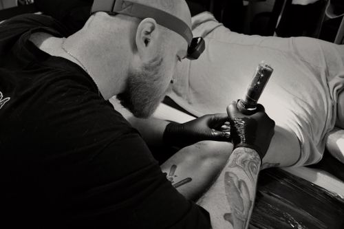 Free A tattoo artist skillfully inks a client's arm in a studio setting. Stock Photo