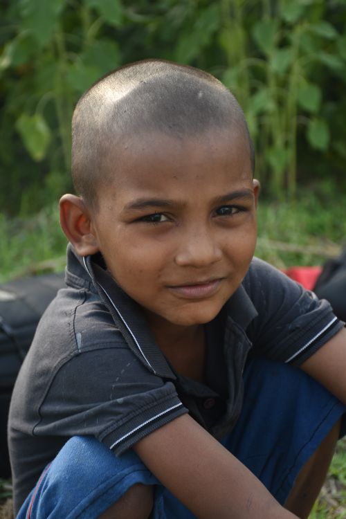 Free Close-up portrait of a young boy sitting outdoors, showing innocence and curiosity. Stock Photo