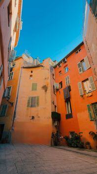 Vibrant courtyard with colorful buildings in Nice, France, under a clear blue sky.