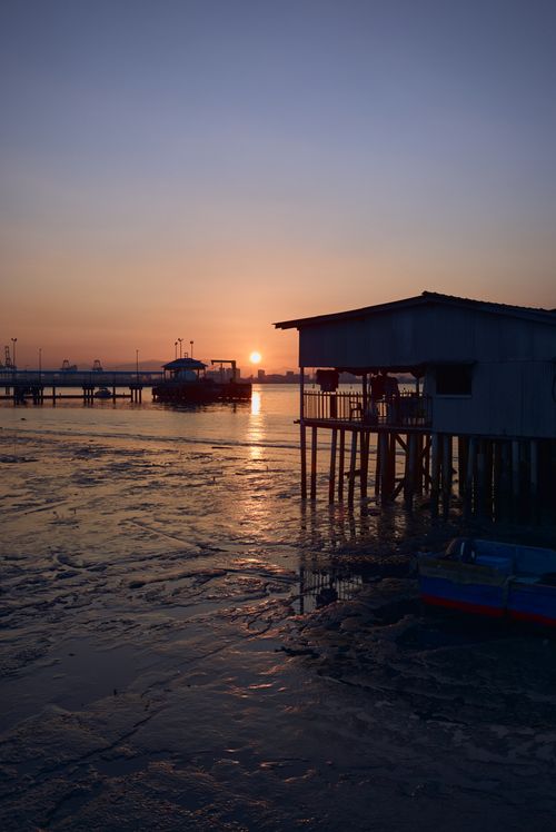 Free Serene sunset view over a coastal fishing village with stilts and boats. Stock Photo