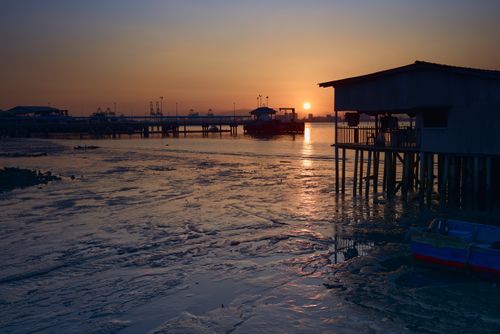 Free Beautiful sunset view over a coastal pier, capturing serene waters and a silhouette building. Stock Photo