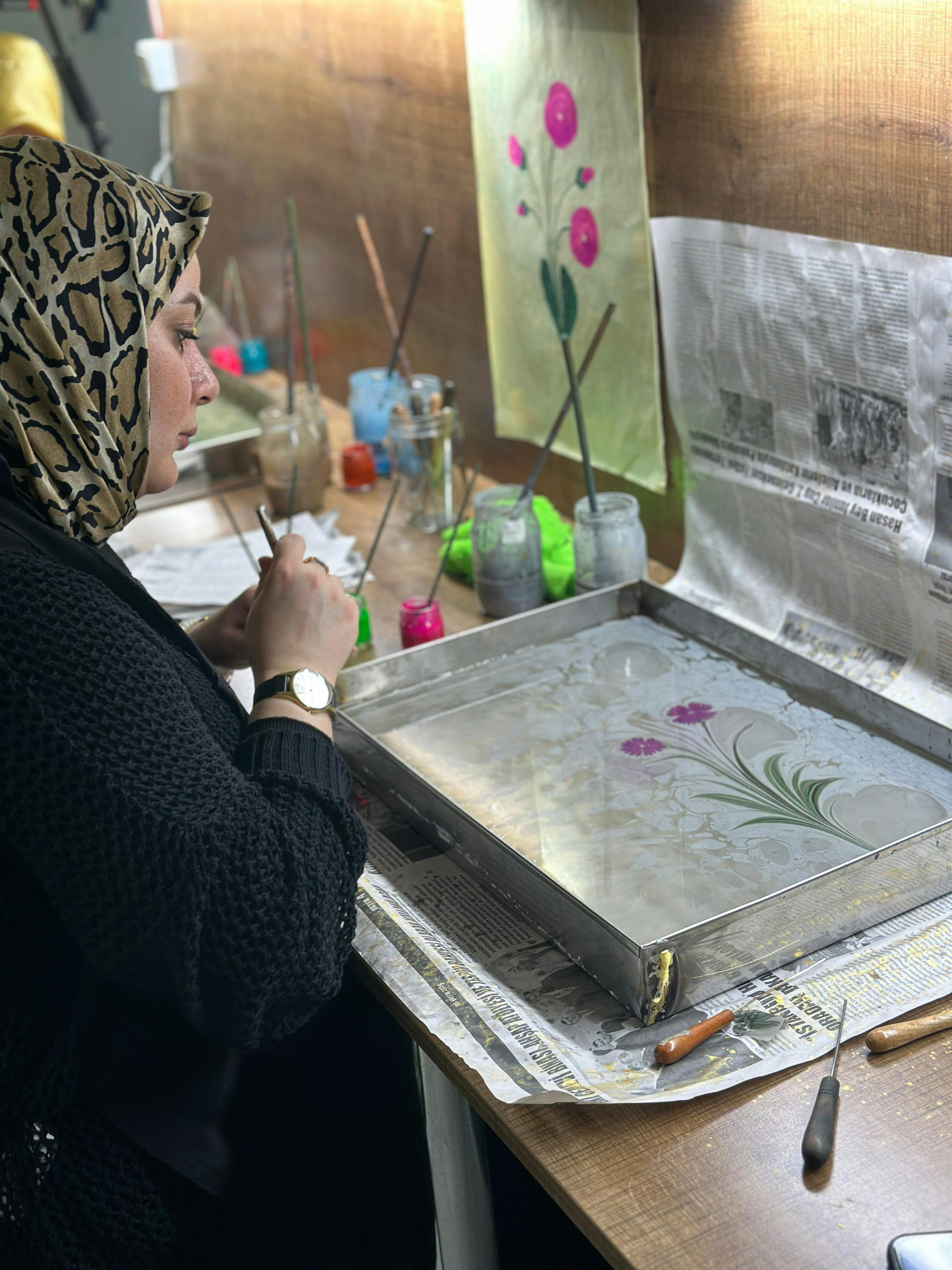 A woman creates intricate traditional Ebru art designs in her studio.