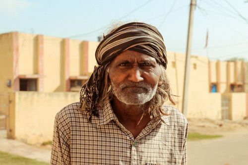 Free Elderly man with turban and checkered shirt standing outdoors. Capturing cultural essence and character. Stock Photo