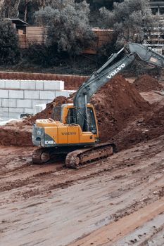 A yellow excavator moves earth at a construction site. Heavy machinery operation captured outdoors.