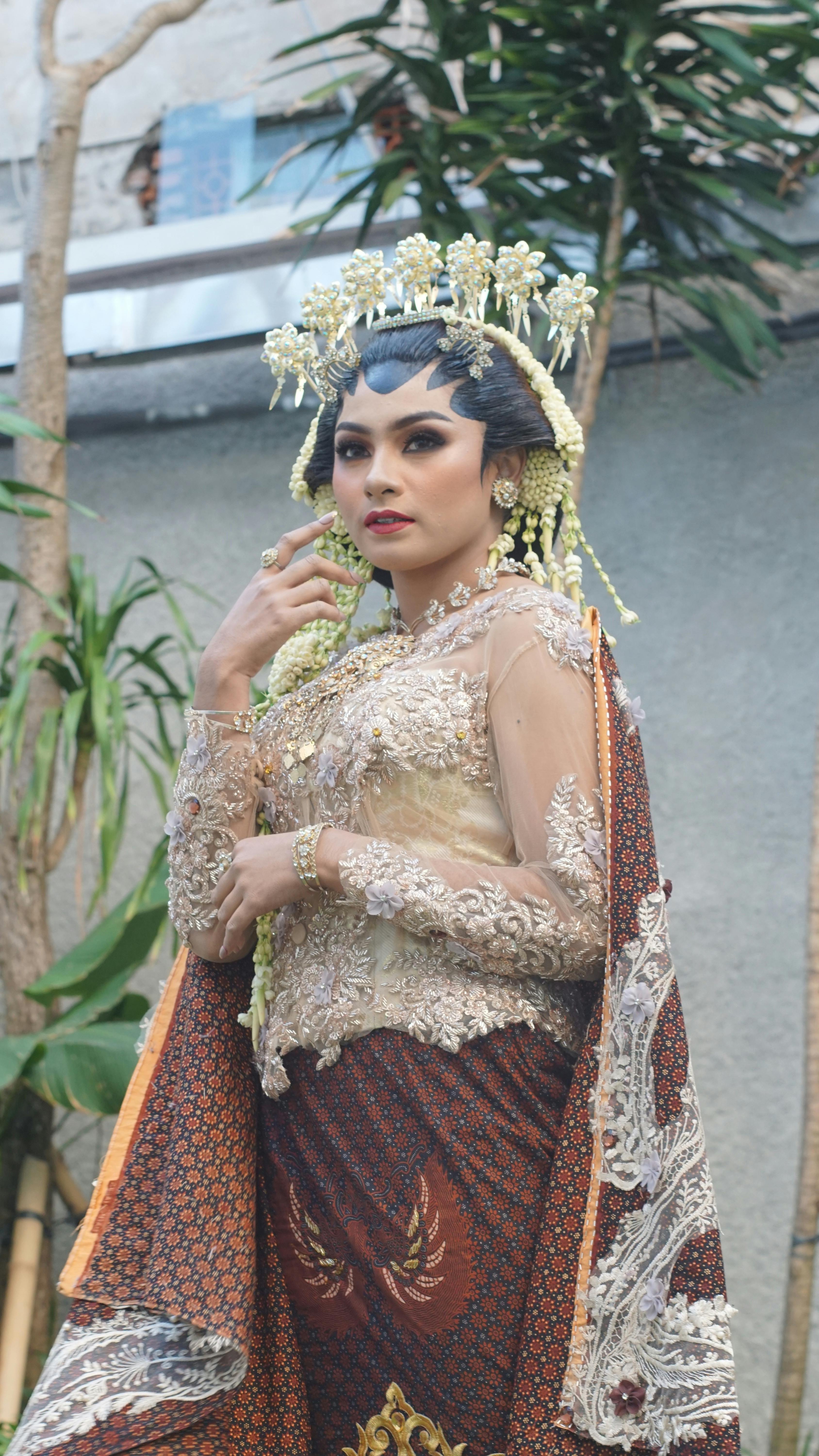 A striking portrait of an Indonesian bride in elaborate traditional attire with intricate makeup.