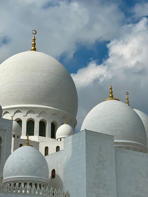 Free A close-up of the majestic domes of Sheikh Zayed Grand Mosque in Abu Dhabi under a partly cloudy sky. Stock Photo