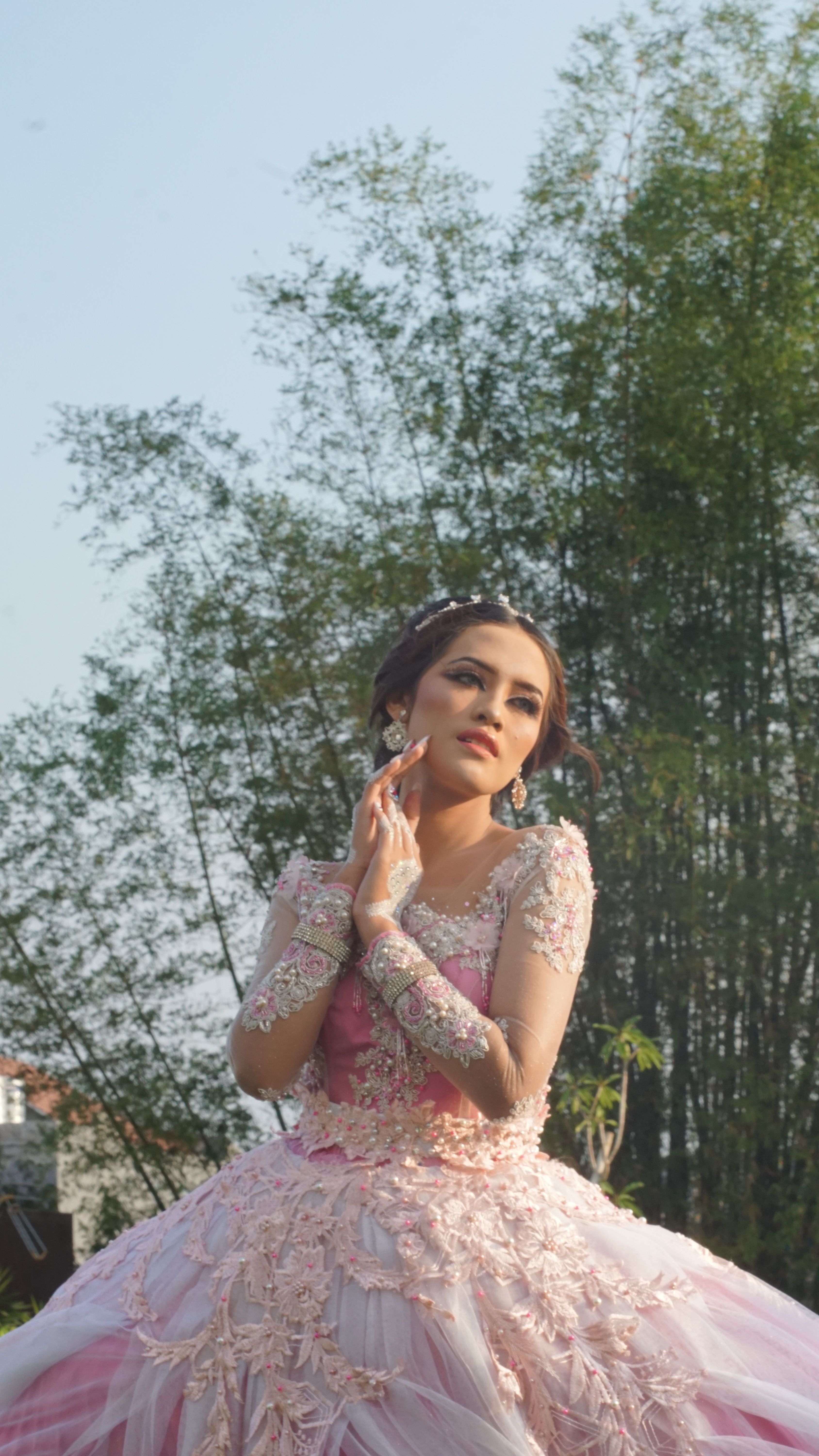 Elegant portrait of a woman in a pink floral gown outdoors in Indonesia, showcasing beauty and grace.