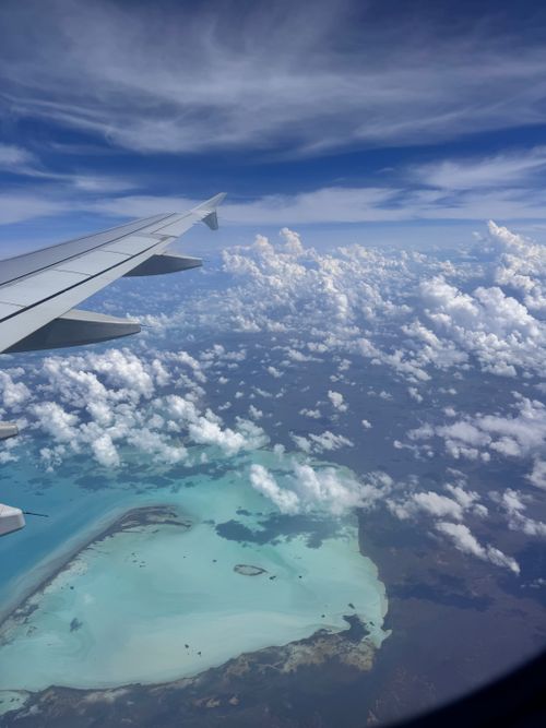 Free A stunning aerial view of tropical waters and coastline from an airplane window. Stock Photo