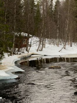 Serene winter scene of a snowy forest and river in Sinettä, Lapland, Finland.