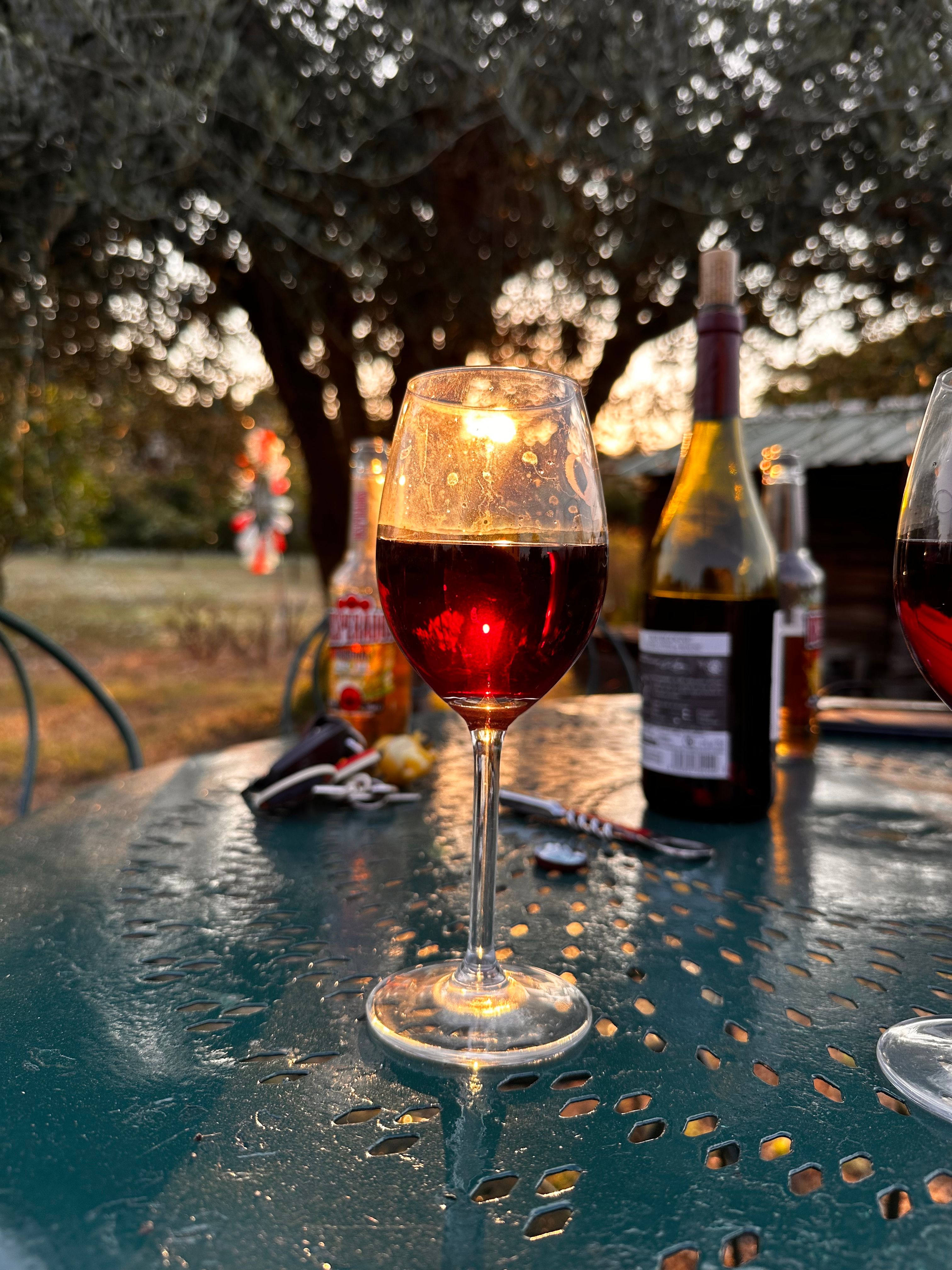 A glass of red wine glowing on an outdoor table at sunset