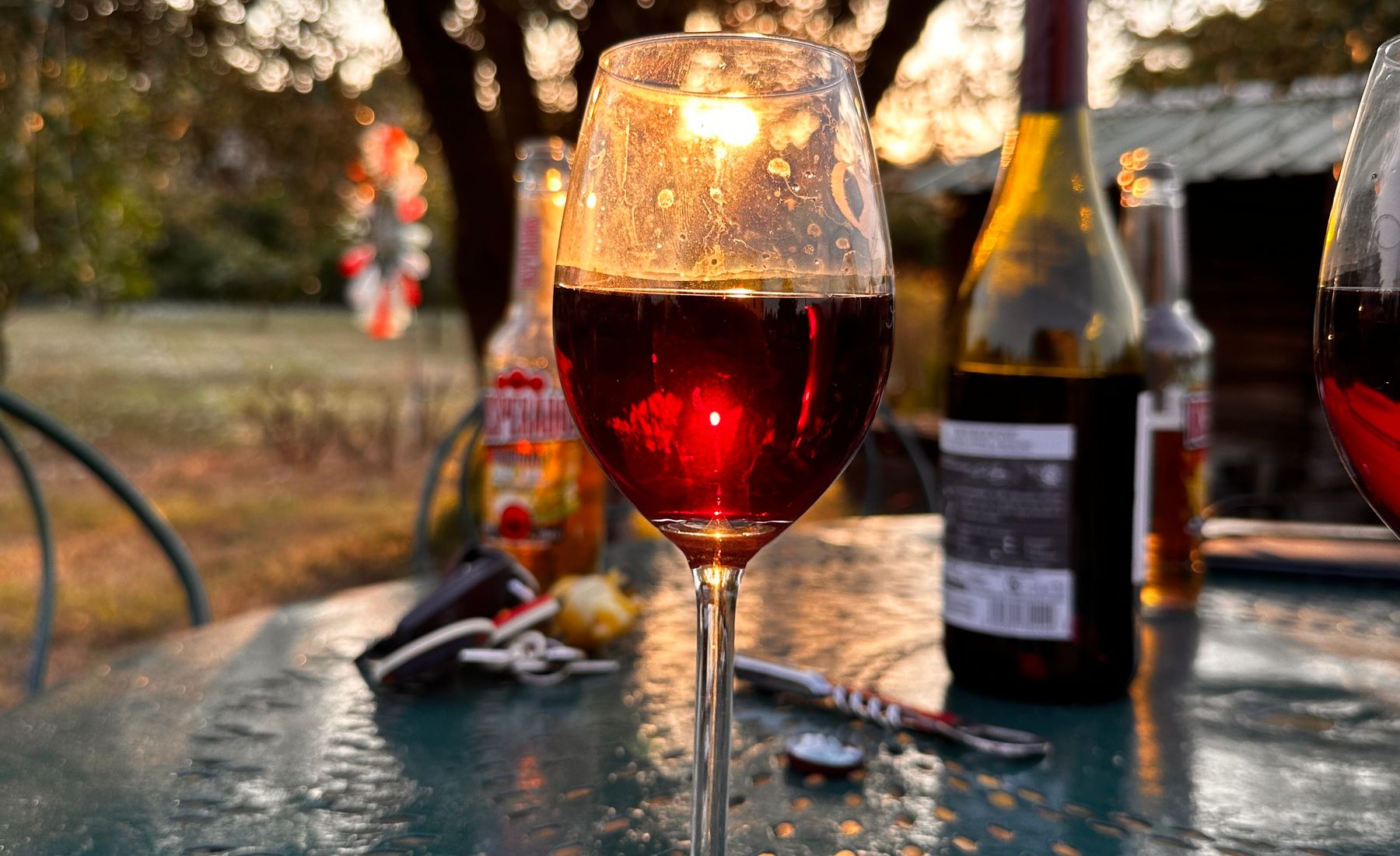 A glass of red wine glowing on an outdoor table at sunset