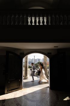 A newlywed couple exits a venue in São Paulo, capturing an elegant wedding moment.