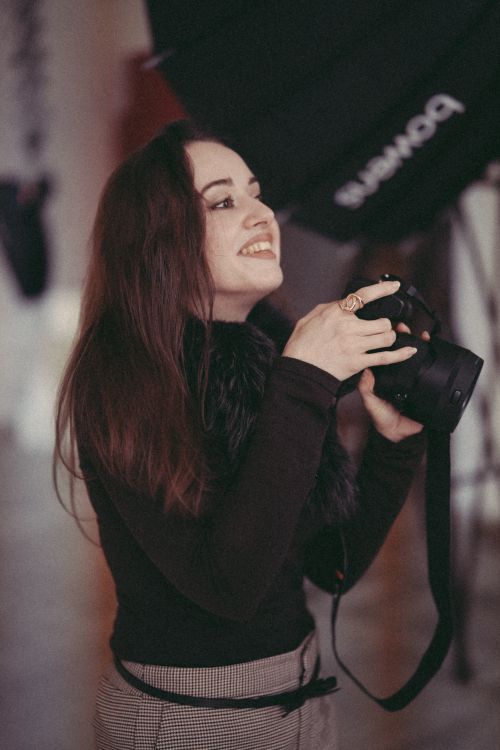 Free Excited female photographer holding a camera, capturing moments in a studio setting. Stock Photo