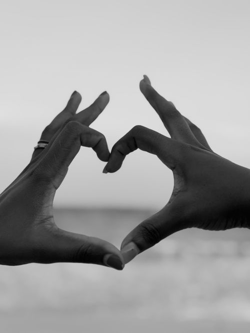 Free Silhouette of hands forming a heart shape against beach backdrop. Capturing love and connection. Stock Photo