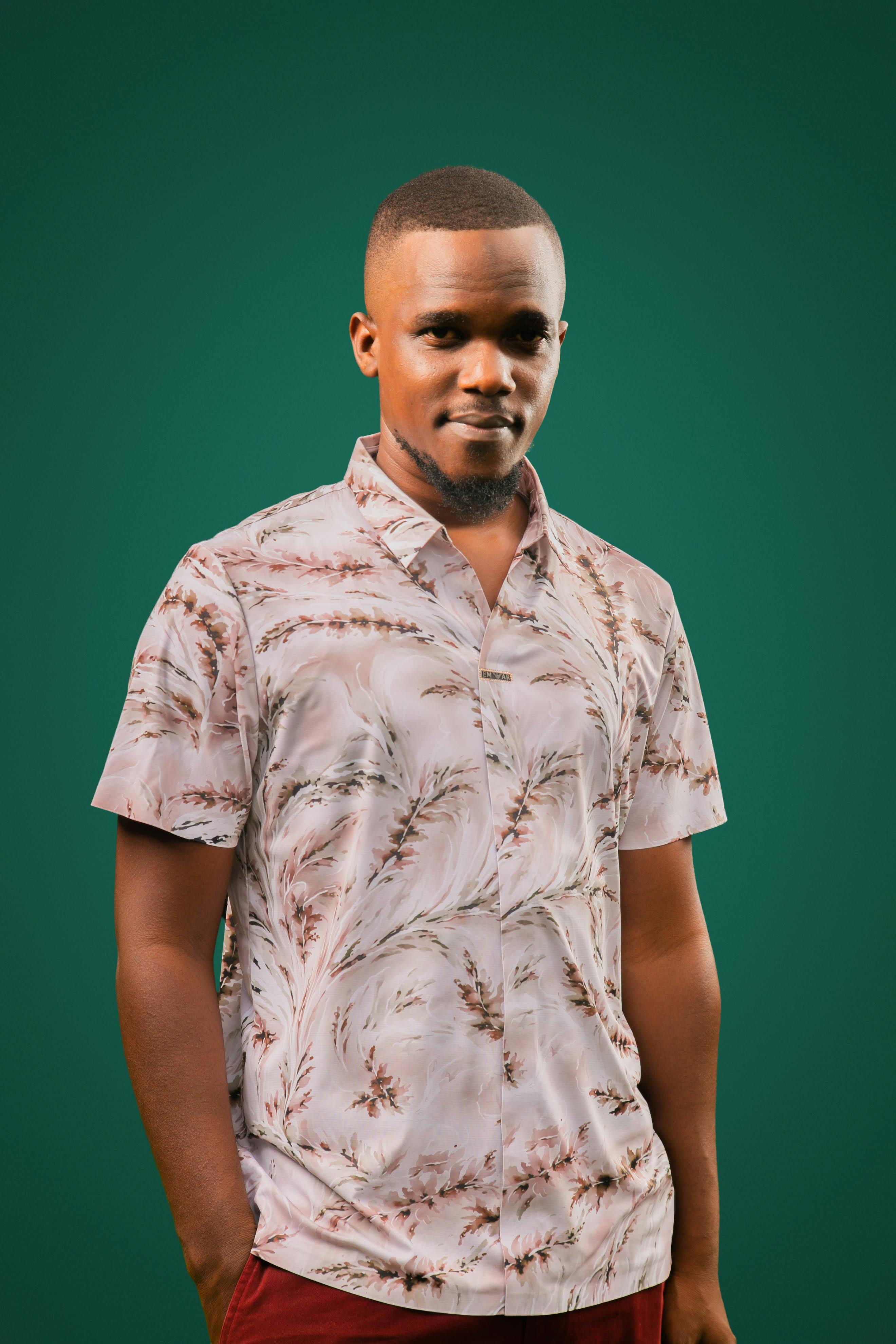 Portrait of a confident man wearing a floral shirt against a green backdrop.