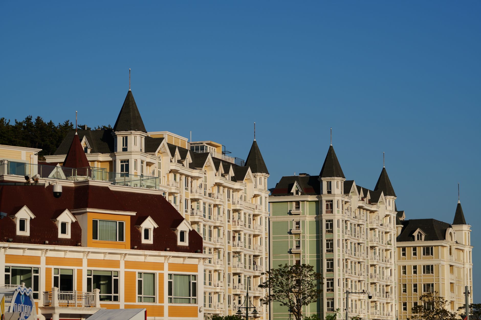 Sunlit European-style buildings in Dalian, showcasing vibrant façades and spire rooftops under a clear blue sky.