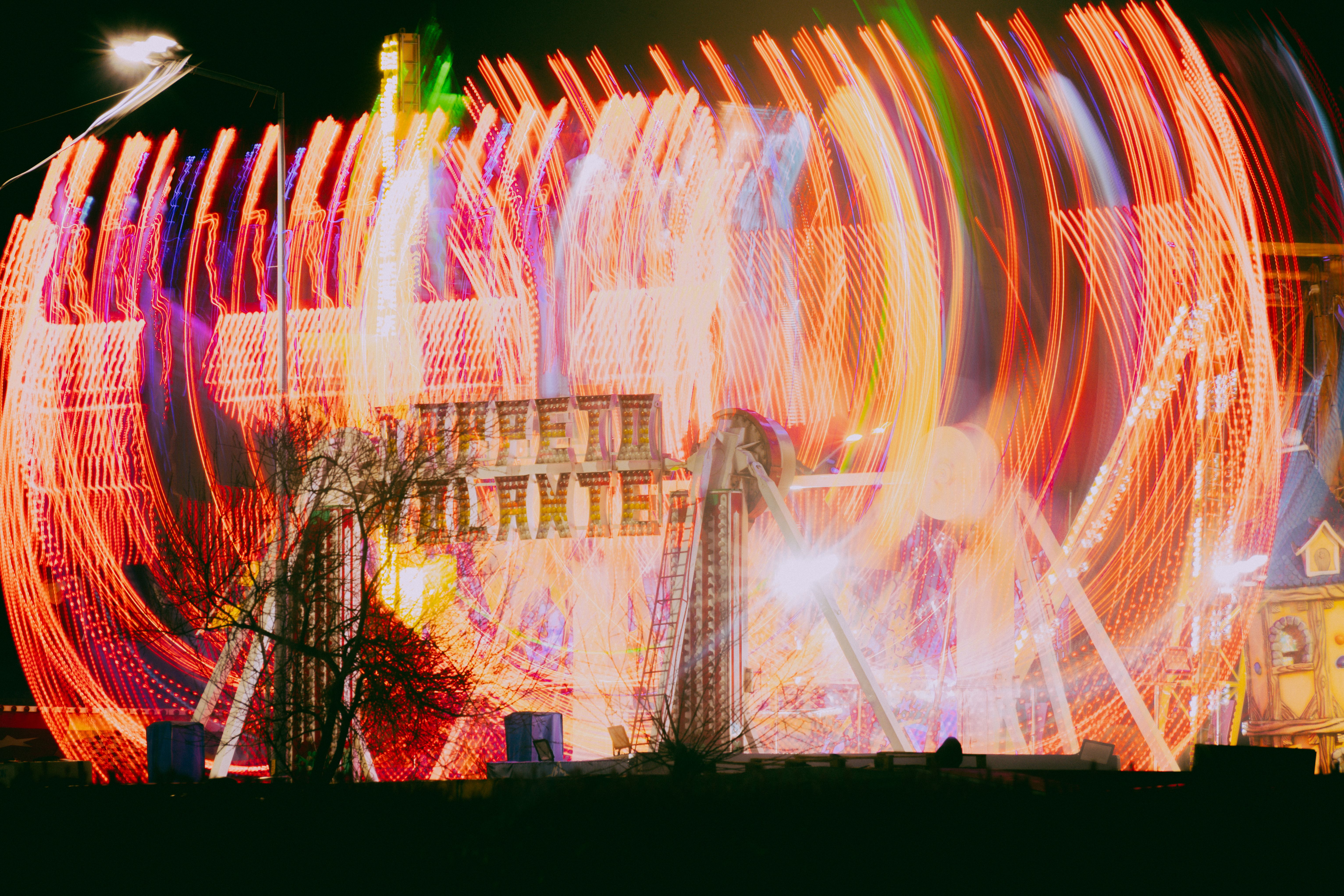 Uzun pozlama çekimiyle elde edilmiş, gece vakti dönen bir lunapark oyuncağının canlı, renkli ışık izleri.