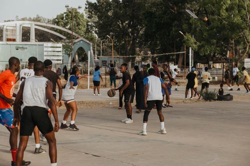 Free Group of young adults playing basketball outdoors on a sunny day. Stock Photo