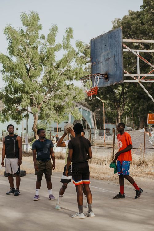 Free A group of young men enjoy a casual basketball game outdoors on a sunny day. Stock Photo