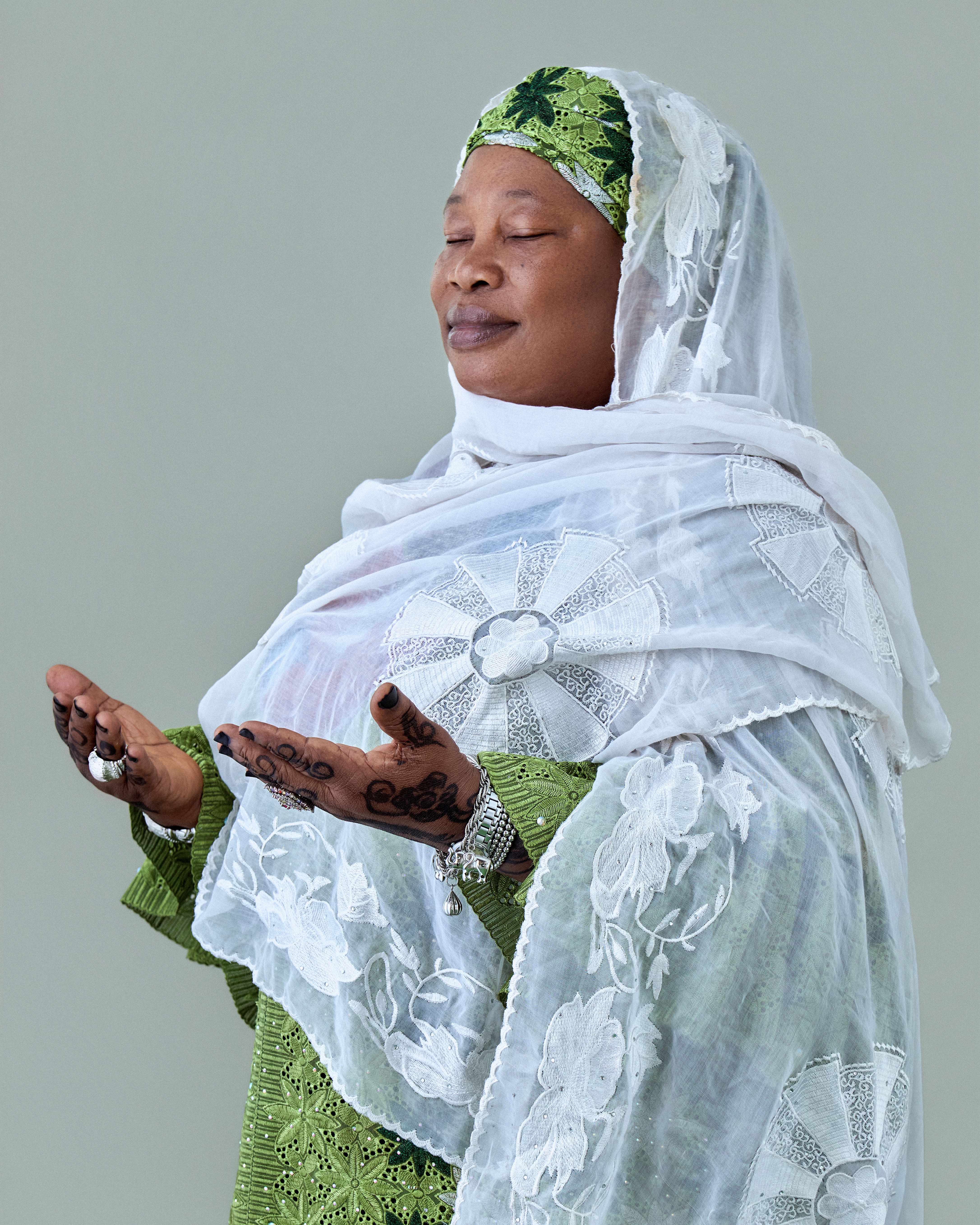A serene African woman in traditional attire, hands raised in prayer, showcasing cultural beauty.