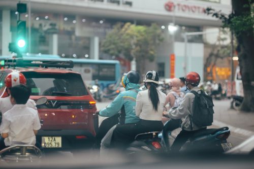 Free Motorbikes and cars at a busy intersection under a green traffic light in an urban environment. Stock Photo