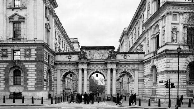 Black and white view of Admiralty Arch, a historic landmark in London with people walking beneath.