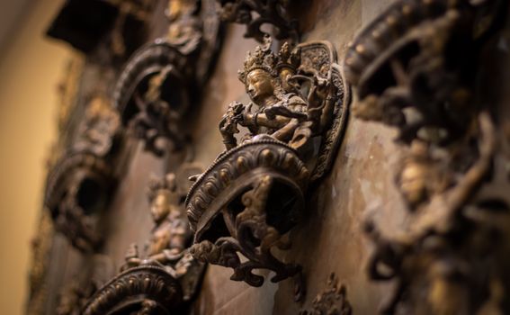 Close-up view of ornate bronze sculptures on a decorative wall, showcasing artistry and craftsmanship.