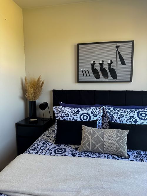 Free A stylish bedroom with patterned bedding and unique wall art enhances a cozy atmosphere. Stock Photo