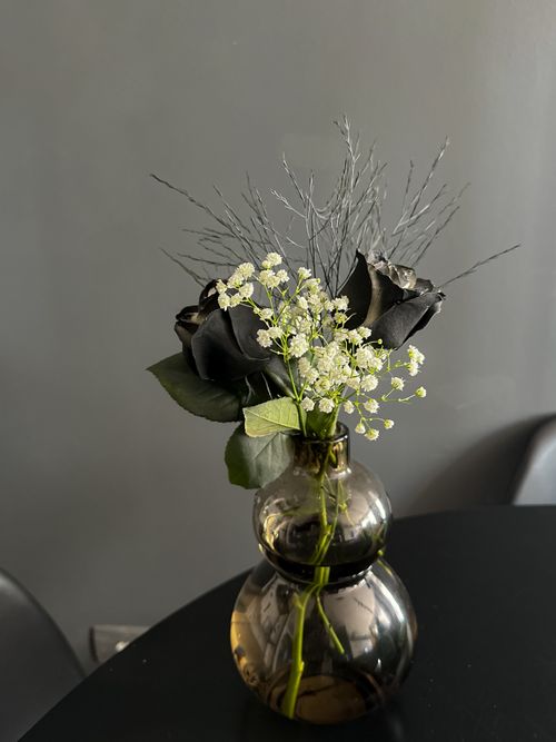 Free Black roses and delicate flowers in a vase on a dark table, perfect for modern decor themes. Stock Photo