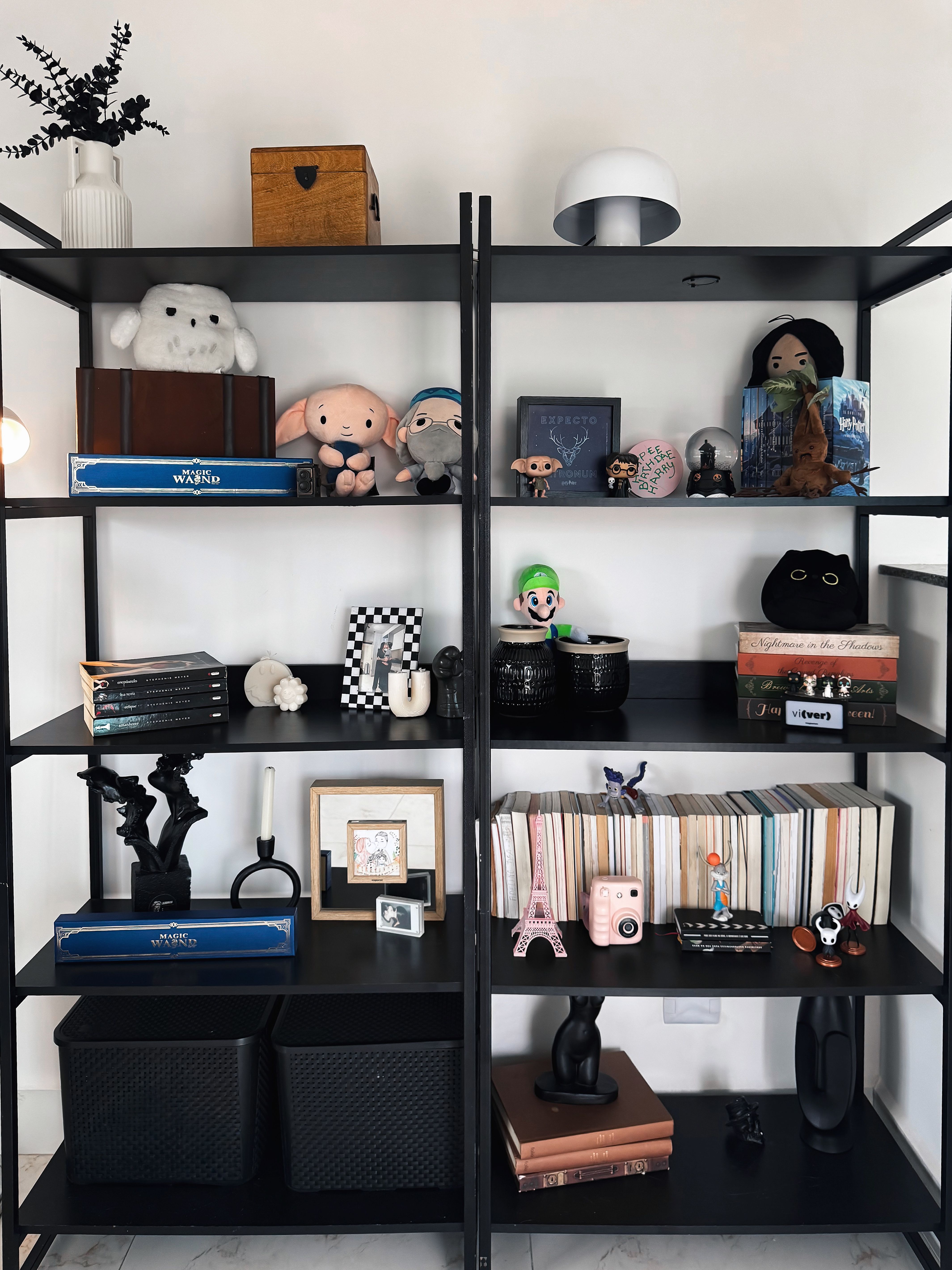 A stylish black bookshelf displaying a mix of plush toys, books, and unique decorative items.