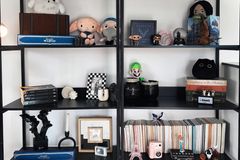 A stylish black bookshelf displaying a mix of plush toys, books, and unique decorative items.