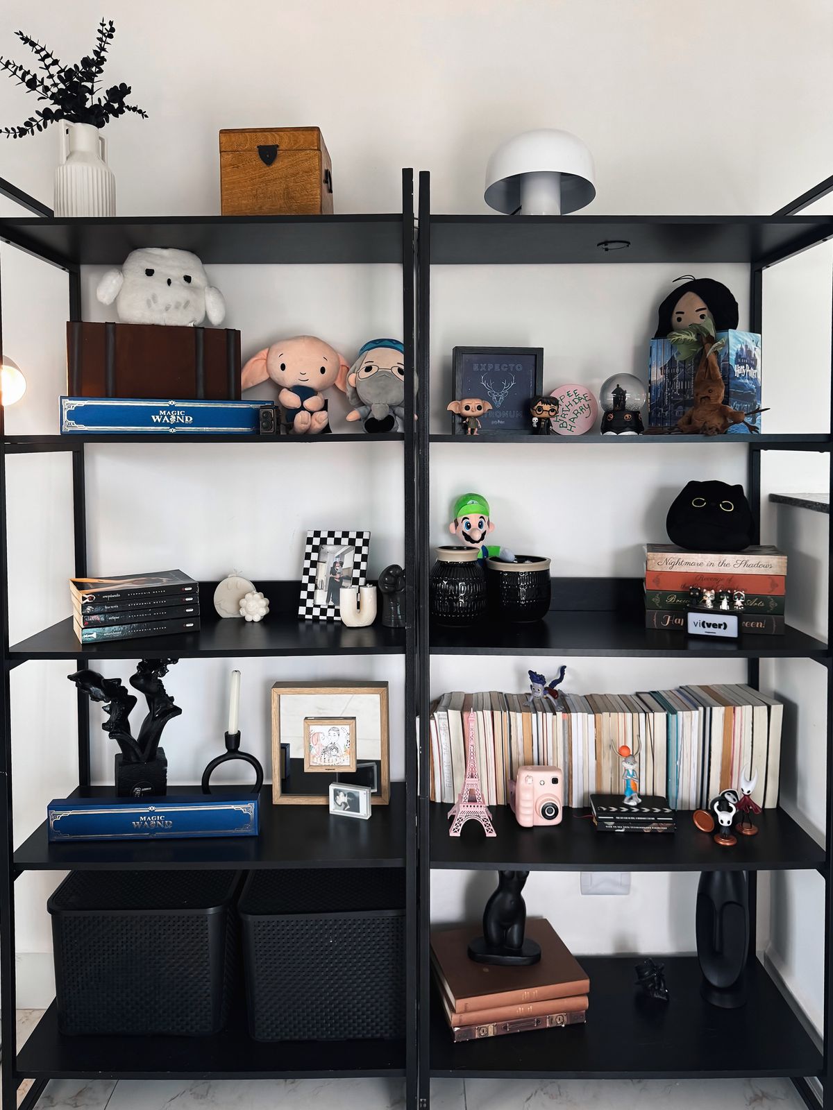 Black bookshelf displaying books, plush toys and decorative items